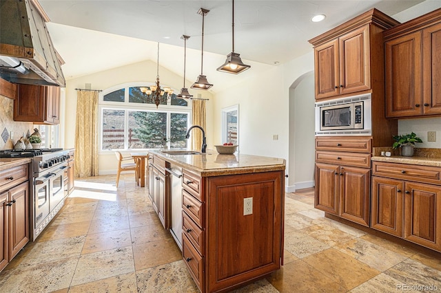 kitchen with arched walkways, lofted ceiling, stone tile flooring, appliances with stainless steel finishes, and a sink