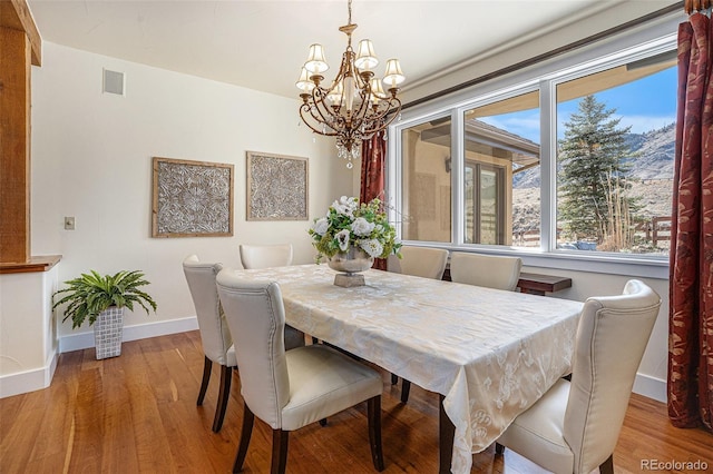 dining area featuring a chandelier, wood finished floors, visible vents, and baseboards