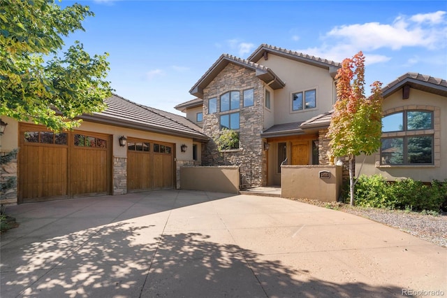 view of front of house featuring a garage, stone siding, concrete driveway, and stucco siding