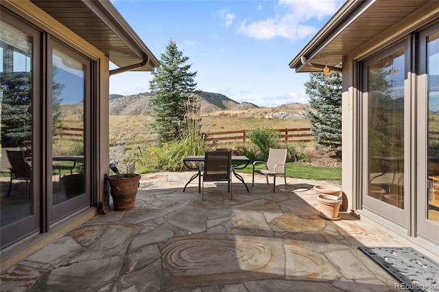 view of patio / terrace featuring outdoor dining area, fence, and a mountain view