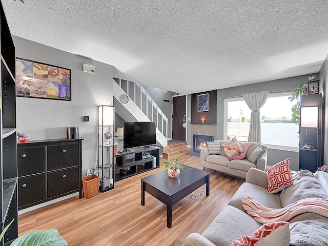 living room featuring wood-type flooring, a textured ceiling, and a tile fireplace