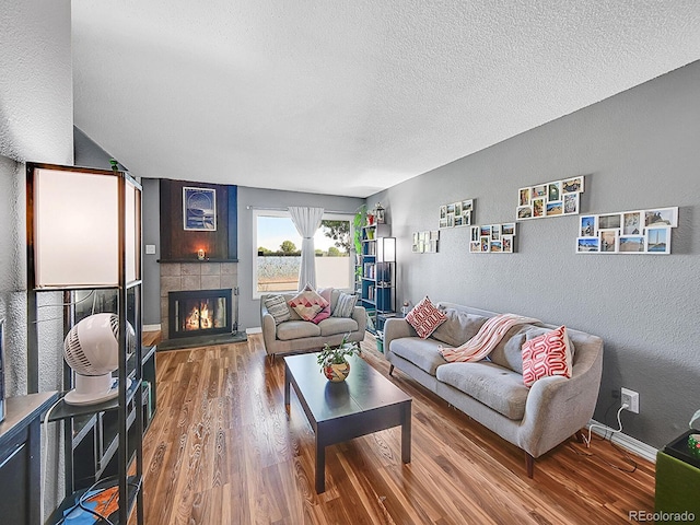 living room with a textured ceiling, a fireplace, and hardwood / wood-style floors