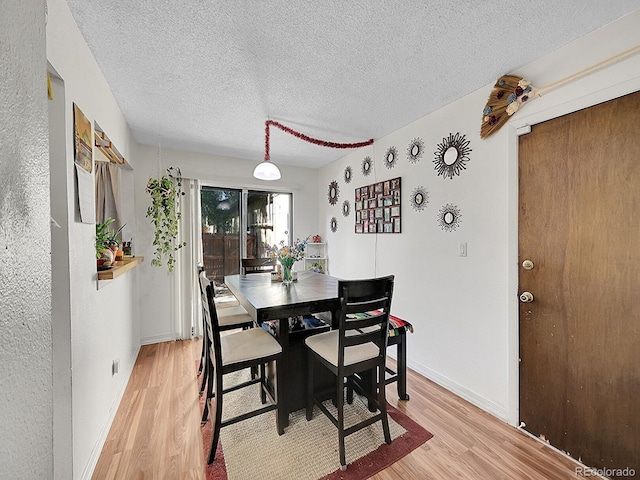 dining area featuring a textured ceiling and light hardwood / wood-style flooring