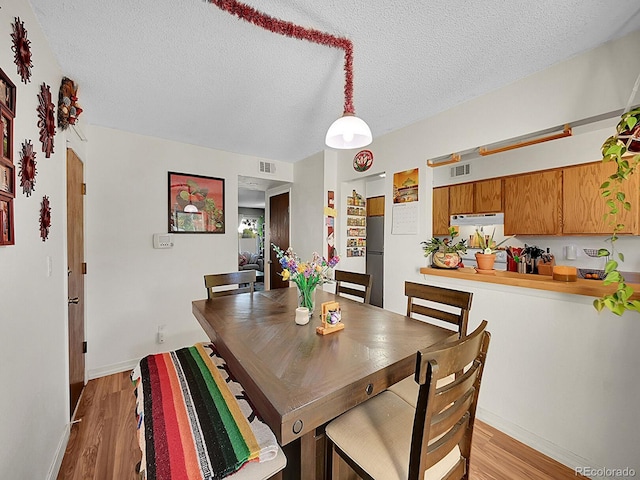 dining space featuring a textured ceiling and light hardwood / wood-style floors