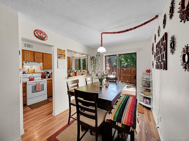 dining room featuring a textured ceiling and light hardwood / wood-style flooring