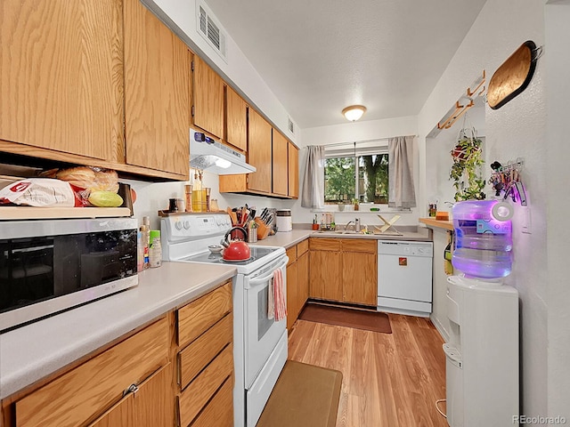 kitchen with white appliances, light hardwood / wood-style floors, sink, and a textured ceiling