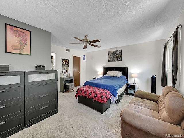 bedroom featuring light carpet, ceiling fan, and a textured ceiling