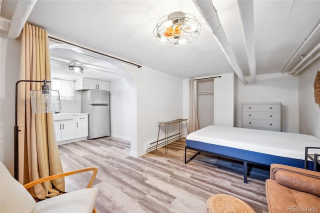 bedroom featuring stainless steel refrigerator, sink, light hardwood / wood-style floors, and baseboard heating