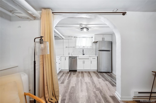 kitchen with a baseboard radiator, appliances with stainless steel finishes, sink, and white cabinets