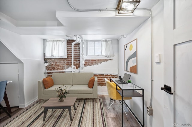 sitting room with hardwood / wood-style floors and brick wall