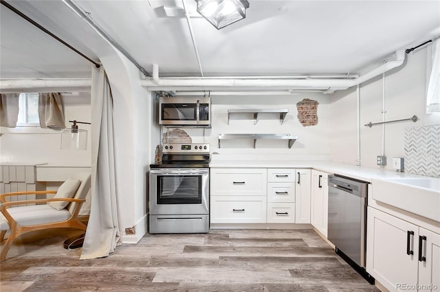 1331 N Ogden St Unit 1, Denver, CO 80218 - kitchen with appliances with stainless steel finishes, white cabinets, light wood-style flooring, and light countertops