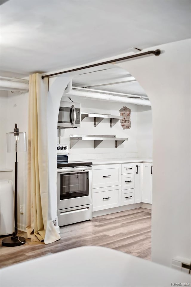 1331 N Ogden St Unit 1, Denver, CO 80218 - kitchen with appliances with stainless steel finishes, white cabinetry, light wood-style flooring, and arched walkways