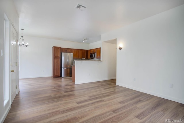 unfurnished living room with light hardwood / wood-style floors and a notable chandelier