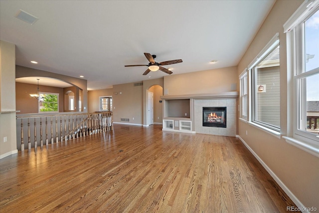 22873 E David Pl, Aurora, CO 80016 - unfurnished living room with wood finished floors, arched walkways, ceiling fan, a fireplace, and a chandelier