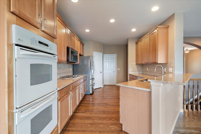 22873 E David Pl, Aurora, CO 80016 - kitchen featuring a peninsula, double oven, wood finished floors, recessed lighting, and decorative backsplash
