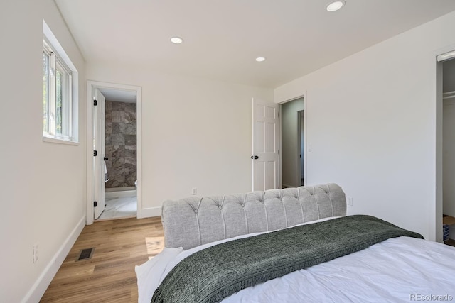 bedroom with ensuite bath and light hardwood / wood-style flooring