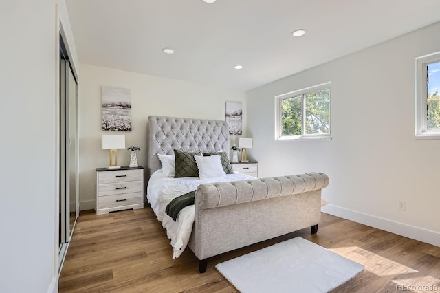 bedroom featuring light hardwood / wood-style floors, multiple windows, and a closet