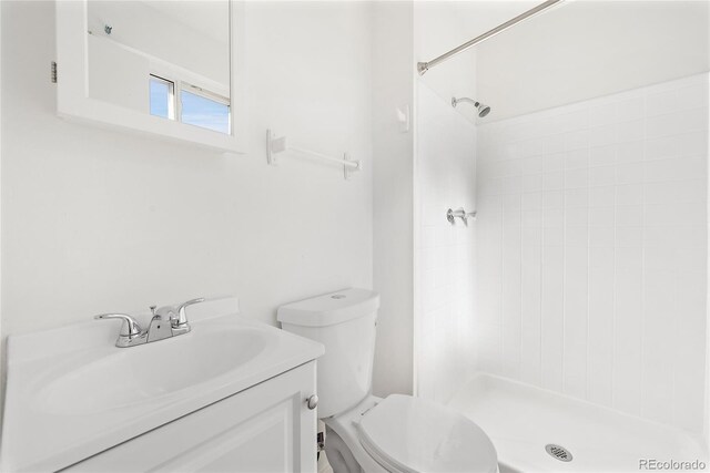 bathroom featuring vanity, a tile shower, and toilet