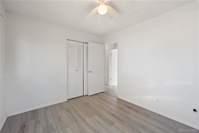 unfurnished bedroom featuring light hardwood / wood-style flooring, a textured ceiling, a closet, and ceiling fan