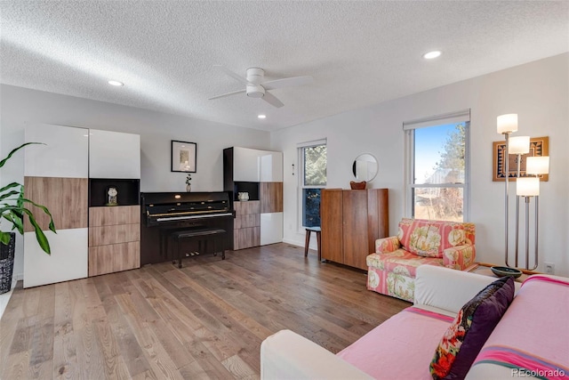 living room with recessed lighting, ceiling fan, a textured ceiling, and light wood finished floors