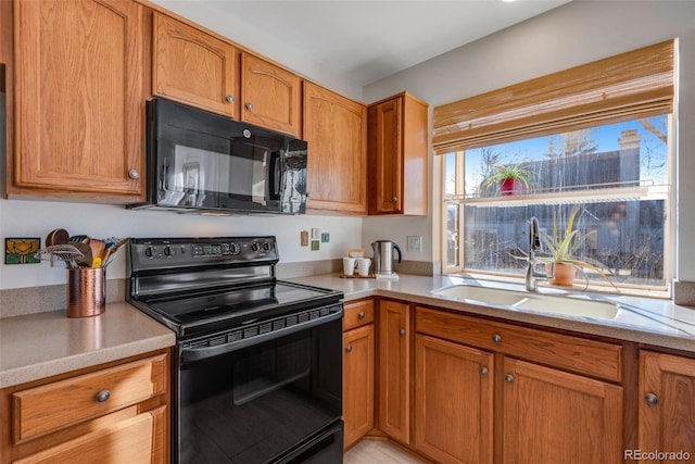 kitchen with brown cabinets, black appliances, light countertops, and a sink