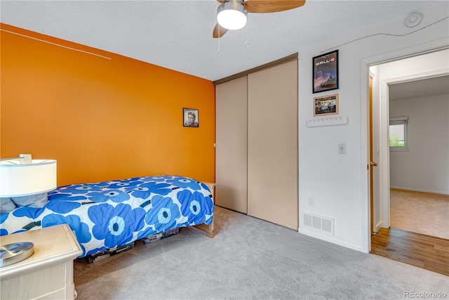 bedroom with a textured ceiling, a closet, visible vents, and carpet flooring