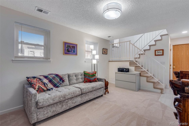 living area with light carpet, visible vents, stairway, and baseboards