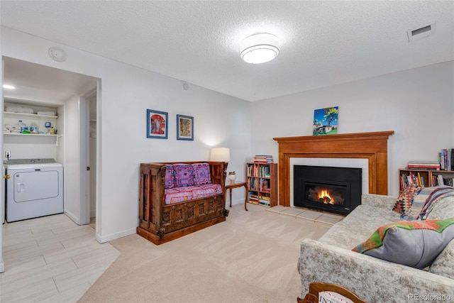 living room with baseboards, visible vents, washer / clothes dryer, a textured ceiling, and a fireplace