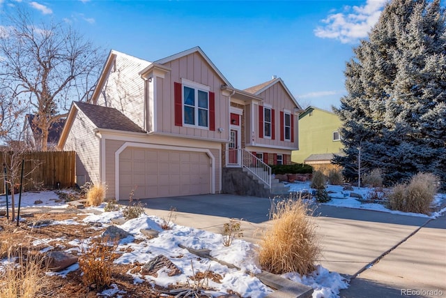 split foyer home with board and batten siding, concrete driveway, fence, and an attached garage