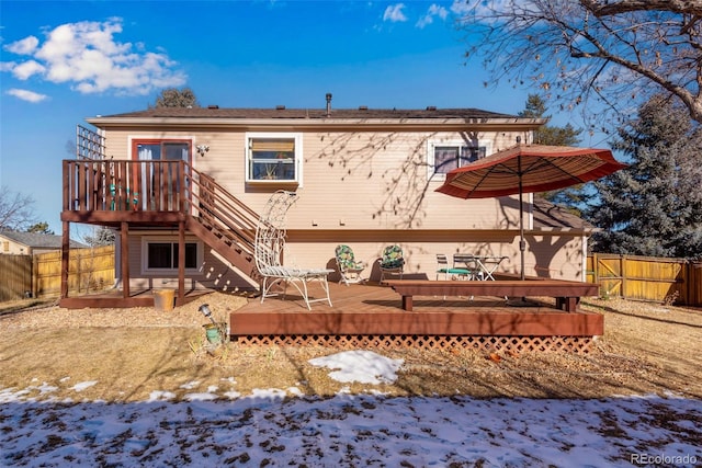 snow covered house featuring stairway, fence, and a wooden deck