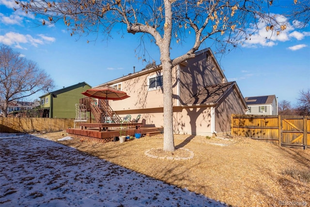 rear view of house with a deck, fence, and a gate