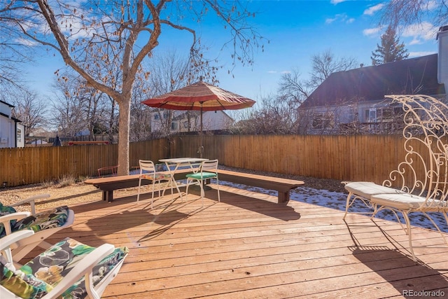 wooden terrace with outdoor dining area and a fenced backyard