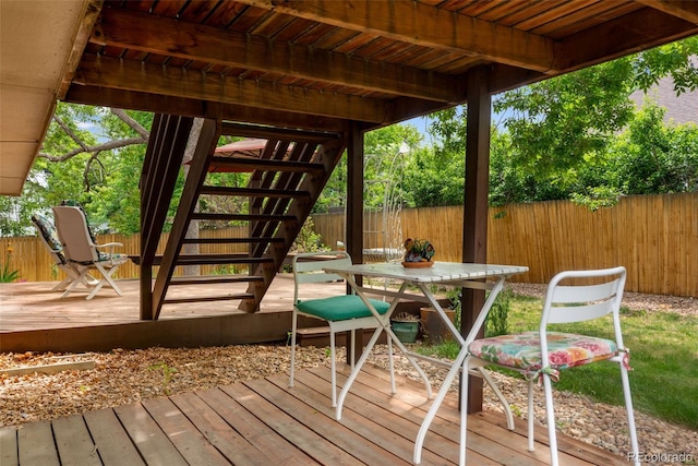 wooden terrace featuring a fenced backyard, stairs, and outdoor dining space