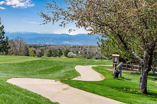 view of property's community with a mountain view, golf course view, and a lawn