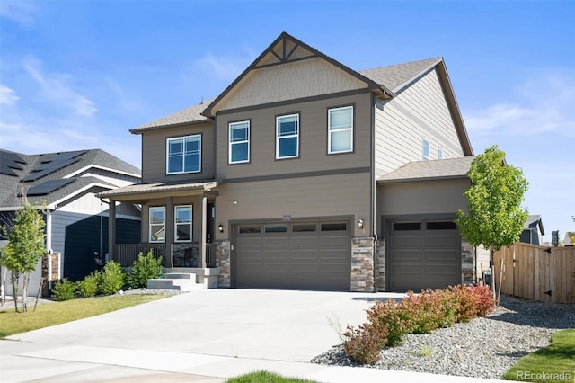 craftsman house featuring driveway, stone siding, an attached garage, and fence