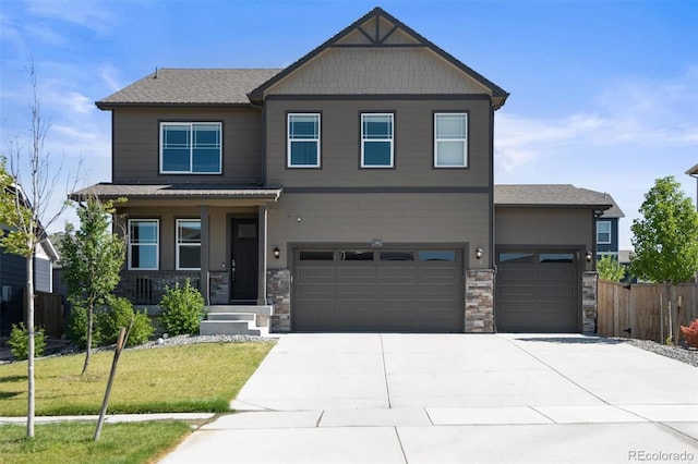 craftsman-style home featuring concrete driveway, an attached garage, covered porch, fence, and a front yard