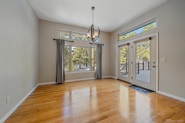 unfurnished dining area with an inviting chandelier and light wood-type flooring