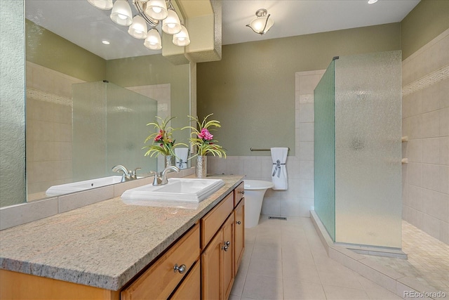 bathroom featuring vanity, tile patterned floors, tile walls, and tiled shower