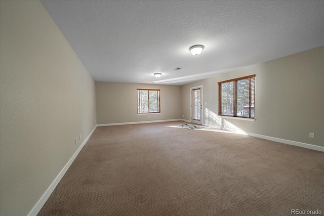 carpeted empty room featuring a textured ceiling