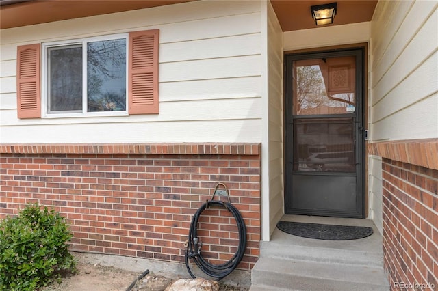 doorway to property with brick siding