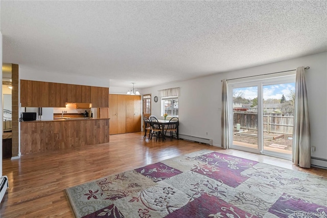 living area featuring wood finished floors, a textured ceiling, baseboard heating, and a chandelier