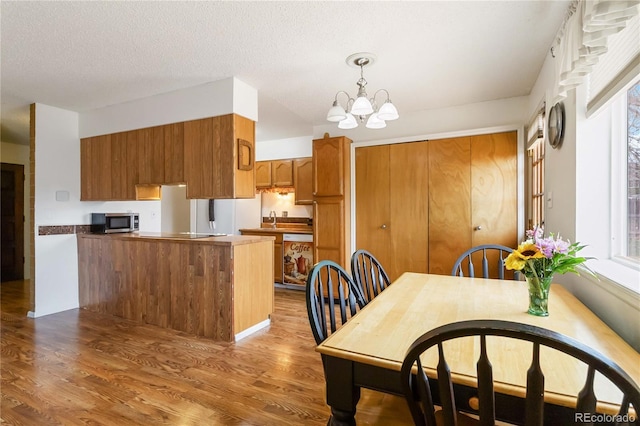 dining space with wood finished floors, a chandelier, and a textured ceiling