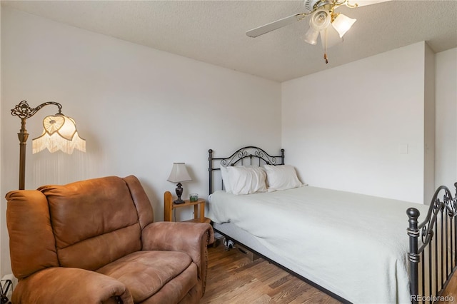 bedroom featuring wood finished floors, a textured ceiling, and a ceiling fan