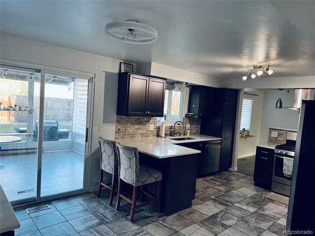 kitchen featuring ceiling fan, tasteful backsplash, a kitchen breakfast bar, kitchen peninsula, and appliances with stainless steel finishes