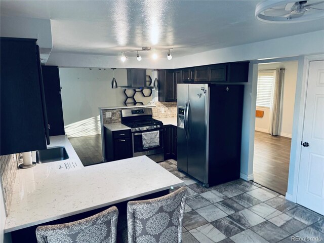 kitchen with a kitchen breakfast bar, kitchen peninsula, ceiling fan, appliances with stainless steel finishes, and wood-type flooring