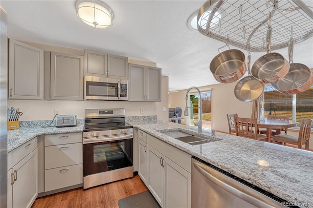 1786 Wintergreen Pl, Loveland, CO 80537 - kitchen with light wood-style flooring, a sink, appliances with stainless steel finishes, gray cabinets, and light stone countertops