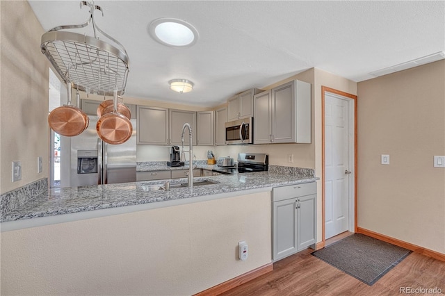 1786 Wintergreen Pl, Loveland, CO 80537 - kitchen with stainless steel appliances, light wood-type flooring, gray cabinets, and a peninsula