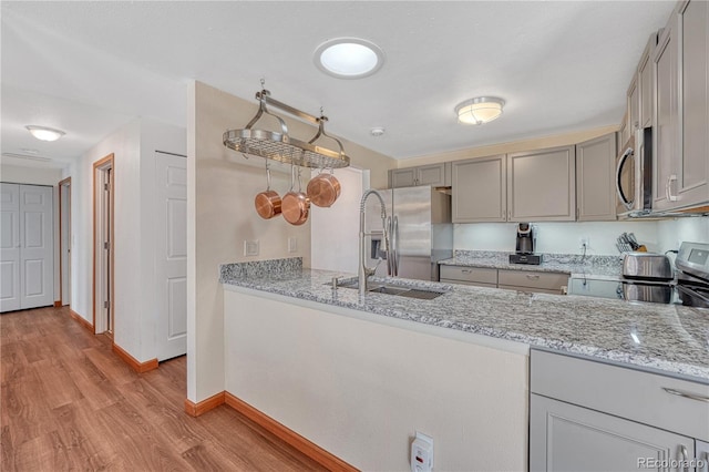 1786 Wintergreen Pl, Loveland, CO 80537 - kitchen featuring light stone counters, gray cabinetry, a sink, appliances with stainless steel finishes, and light wood-type flooring