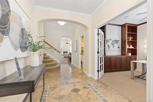 entrance foyer with inlaid floor details, arched walkways, crown molding, stairs, and baseboards