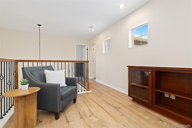 sitting room featuring light wood finished floors, baseboards, arched walkways, and recessed lighting